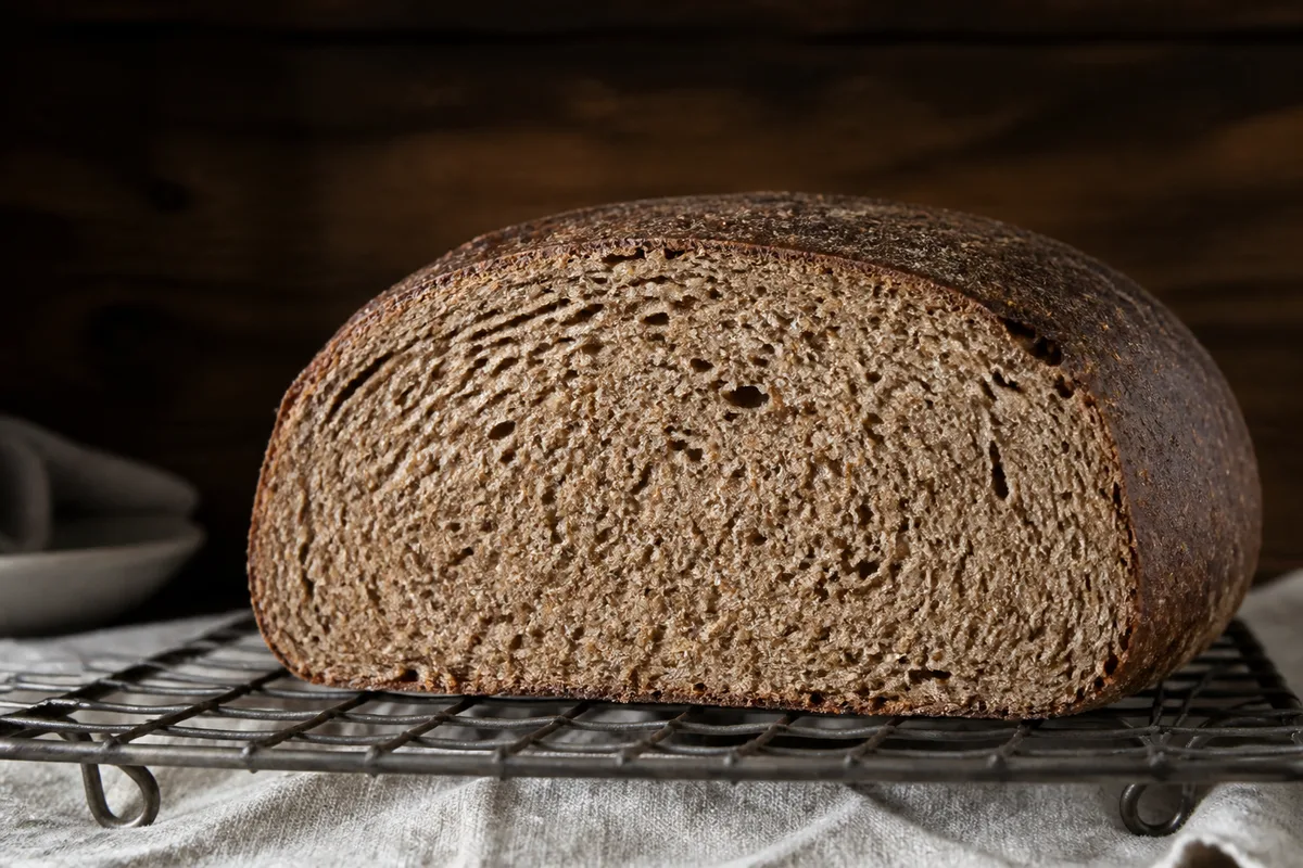 Miche de pain intégral tranchée montrant une mie brune et serrée